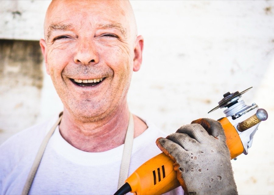 Worker laughing while holding an angle grinder